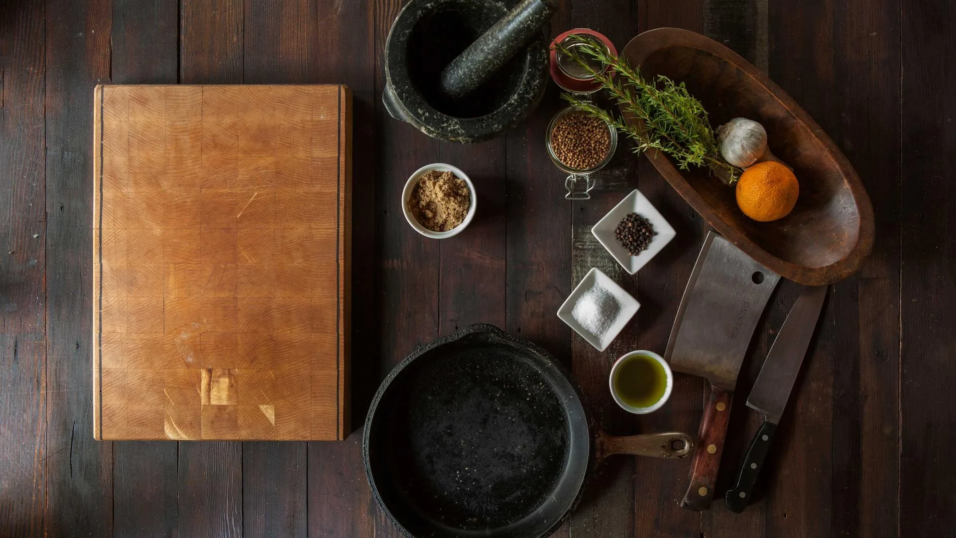 Spices, a mortar and pans laid out on a wooden table