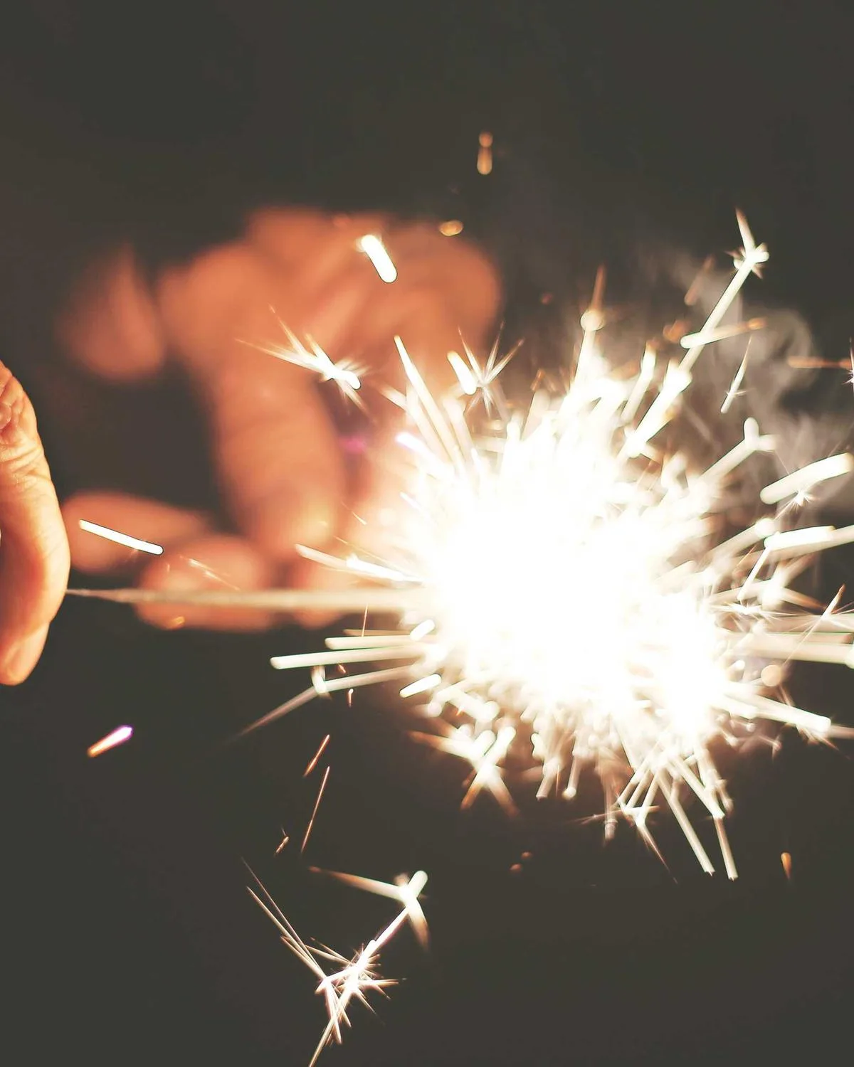 Hand holding a sparkler at night