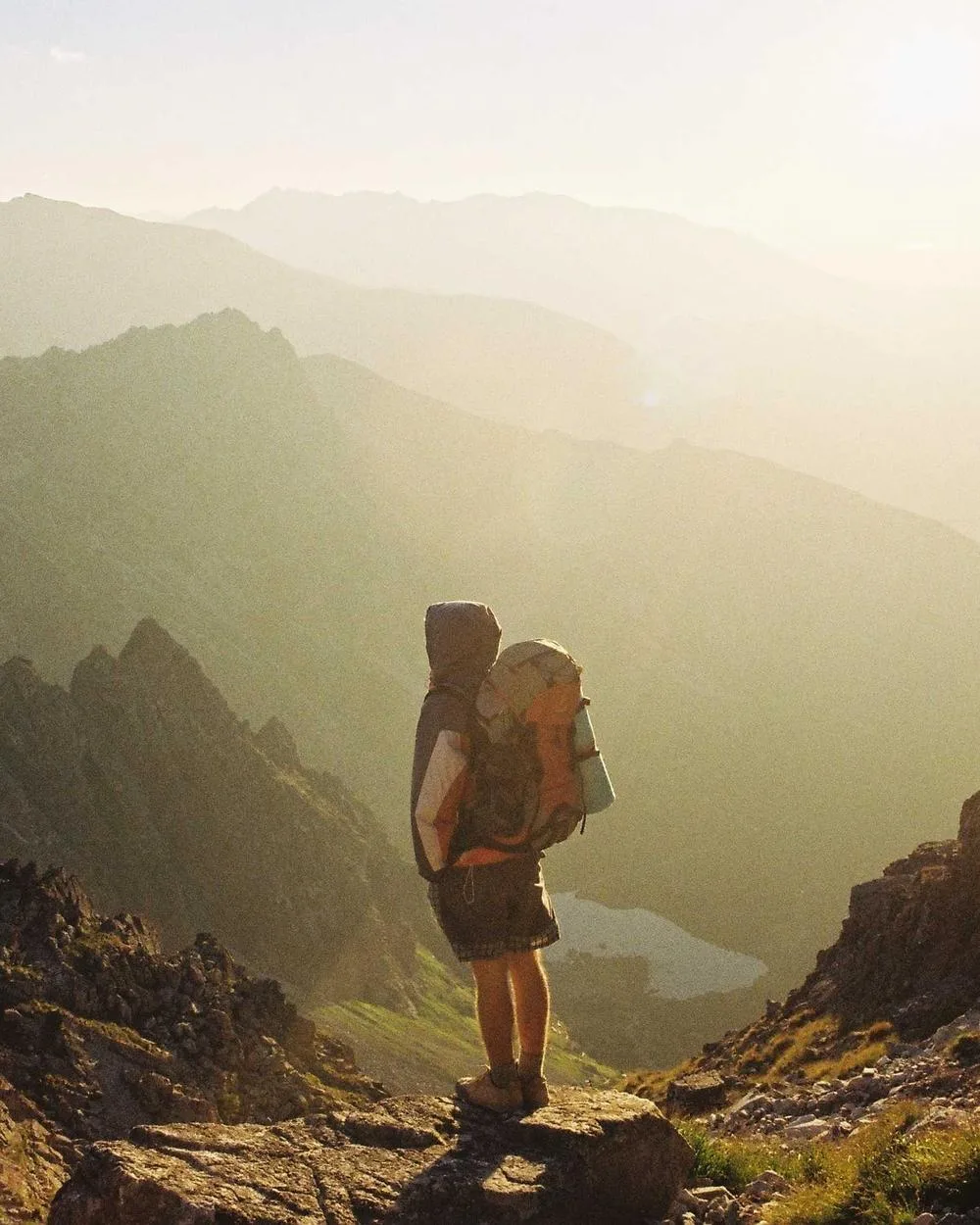 Creator with a backpack looking over a mountain valley