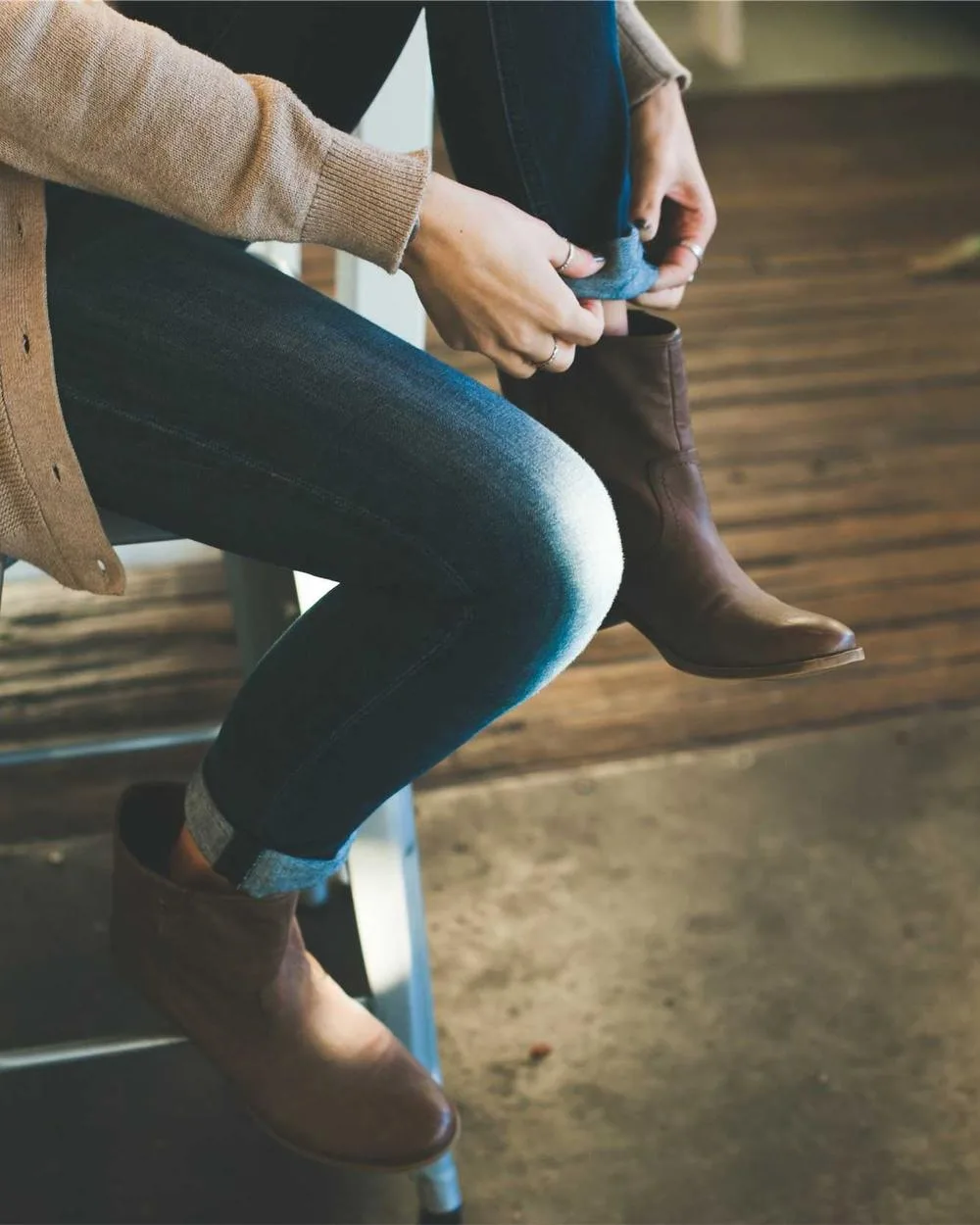 Creator in denim sitting on a concrete ledge, cropped at the waist