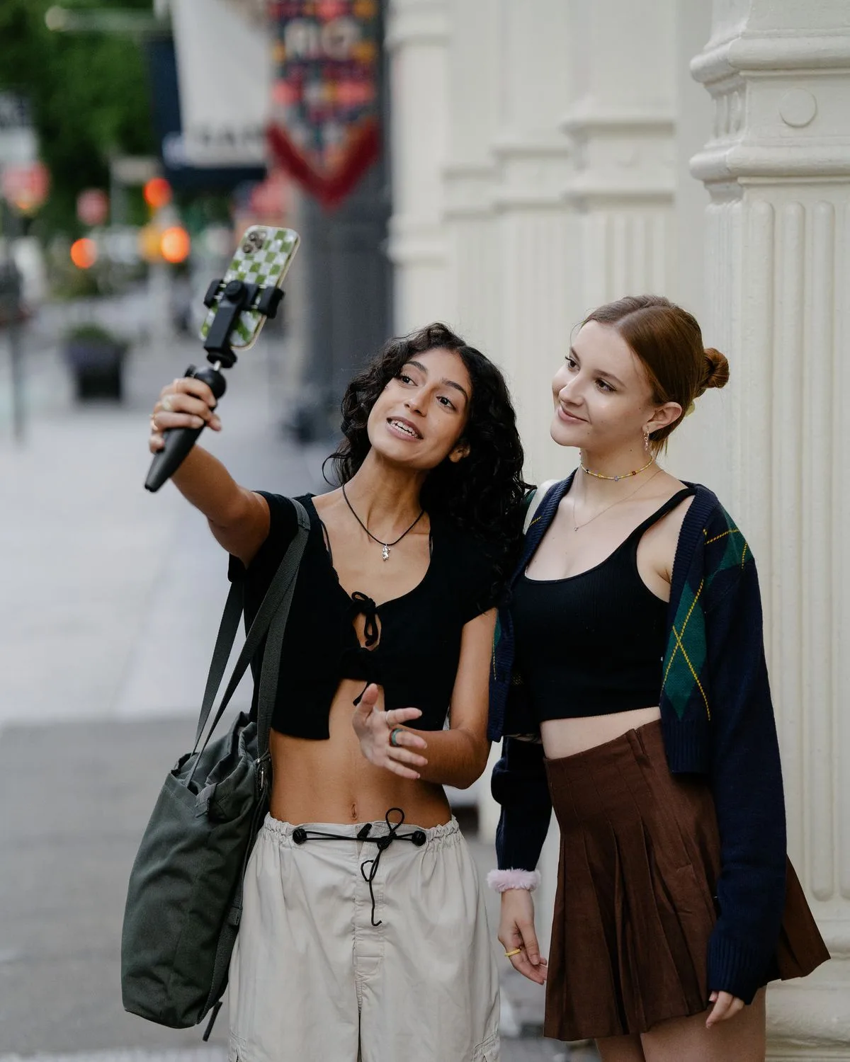 Two creators filming themselves on a city street with a phone on a grip