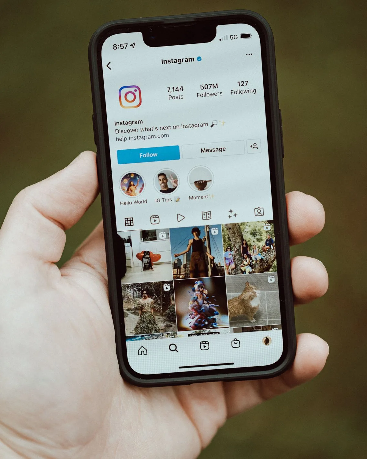 Hand holding a phone open on an Instagram profile grid