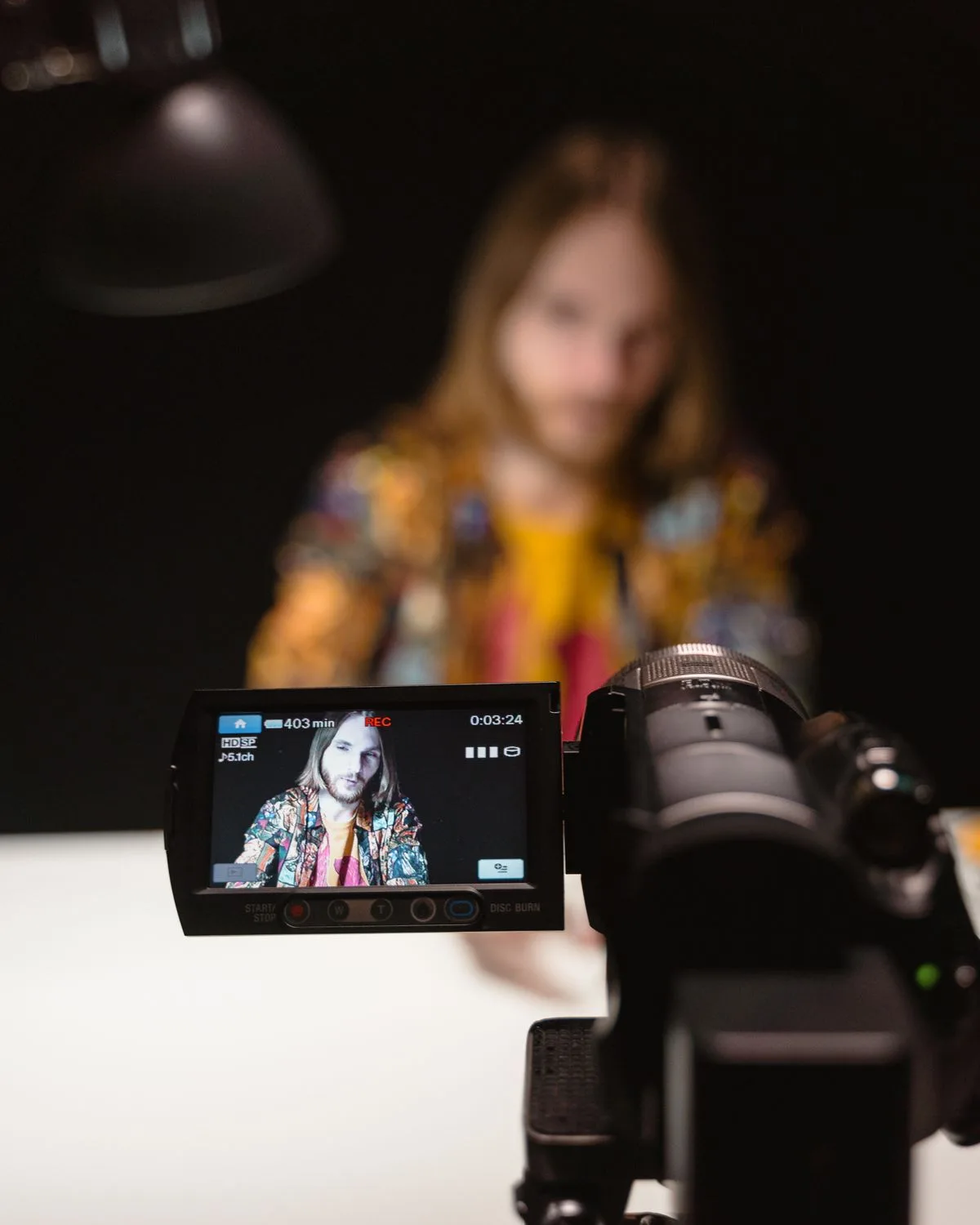 Video camera with its flip screen showing the presenter being recorded